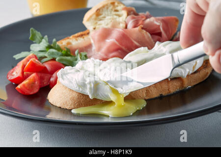 Benedict eggs on buttered wholemeal toast breakfast, knife cuts Stock Photo