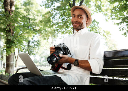 Hipster with laptop in park looking at camera. smiling Stock Photo