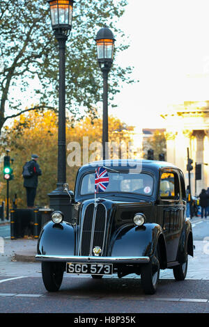 A portrait colour image of a black 1955 Ford Popular drives through a london street with union jack flag on the bonnet Stock Photo