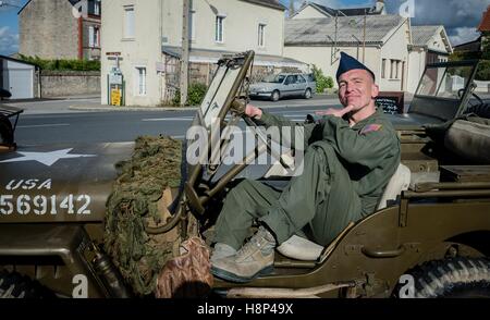 A U.S. soldier poses in the drivers seat of a World War II era Jeep during a D-Day anniversary celebration June 4, 2014 in Caretan, France. Stock Photo