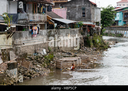 Unidentified Indonesian boy in a slum, washing at the Kali Code bank. The Kali Code is a small river flowing through Yogyakarta, Indonesia. Stock Photo