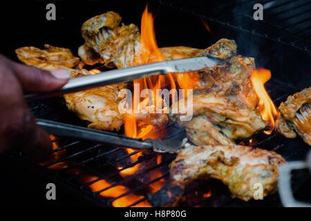 Chef cooking jerk barbecue BBQ chicken on the grill hand turning food Stock Photo