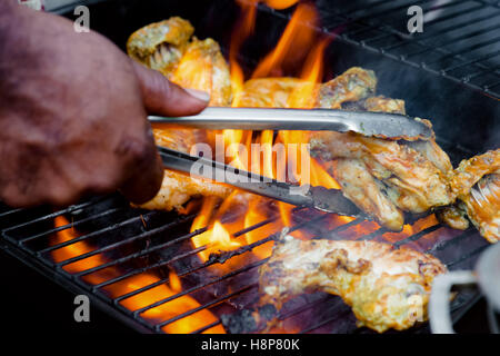 Chef cooking jerk barbecue BBQ chicken on the grill hand turning food Stock Photo