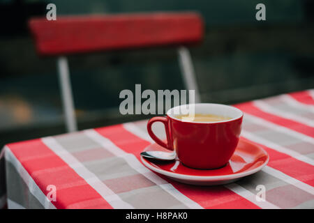 Coffee in red cup on italian style restaurant table, red and white checked cloth Stock Photo