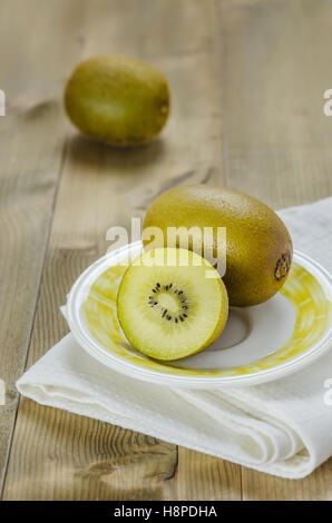 golden kiwi fruit and sliced on dish over wooden background Stock Photo