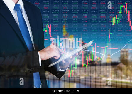 Businessman using digital tablet working with stock market chart in computer screen over the stock market exchange on frankfurt Stock Photo