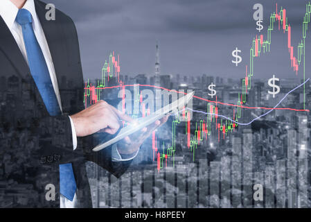 Businessman using digital tablet working with stock market chart in computer screen over the stock market exchange on tokyo city Stock Photo