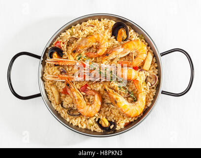 Typical Spanish seafood paella in pan on white background. Top view. Stock Photo