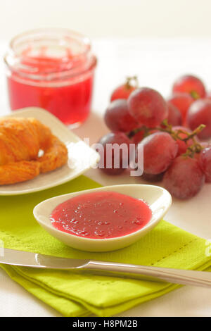 Homemade grape chutney of red grapes in a glass jar on a breakfast table. Stock Photo