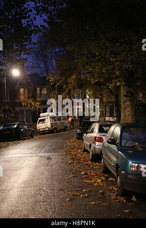 Autumn leaves cover the pavements and streets in a typical South London street after dark on a wet night Stock Photo