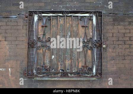 locked bars wrought iron window red rusty grill brick wall Stock Photo