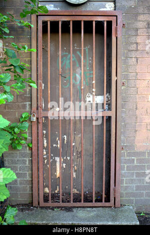 locked bars gate door red rusty grill brick wall Stock Photo
