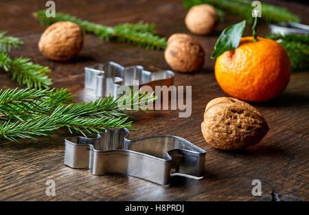 Christmas theme with fir tree branches, orange, walnuts and cookie cutters on wooden table Stock Photo