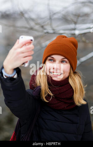 Girl doing selfie. Beautiful blonde in white-red dress does selfie in