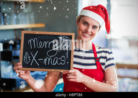 Composite image of portrait of waitress showing slate with merry x-mas sign Stock Photo