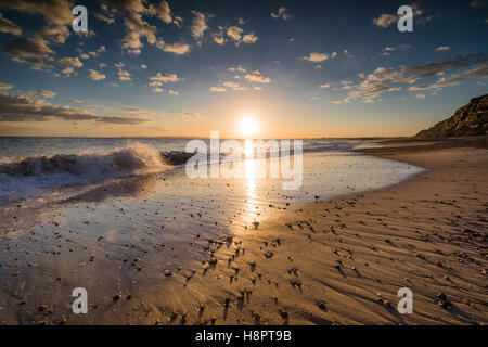 The waves renewing the beach at sunset Stock Photo