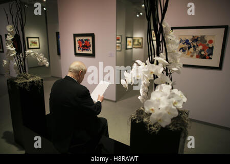 Cologne, Germany. 16th Nov, 2016. A trade fair visitor sits in front of a stand at the Cologne Fine Art fair in Cologne, Germany, 16 November 2016. From 17 to 20 November 2016, around 150 galleries and art dealers are showing old and international art, as well as art from the classic modern era and post-war era. Photo: OLIVER BERG/dpa/Alamy Live News Stock Photo