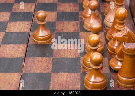 row of vintage wooden pawns on chessboard with focus on second piece Stock Photo