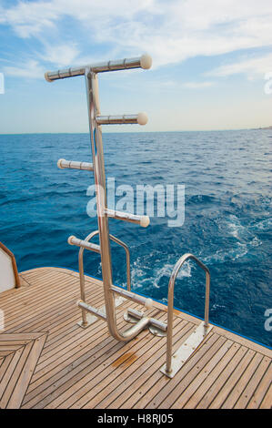 Metal steel ladders on back teak deck of a luxury motor yacht sailing on a tropical ocean Stock Photo