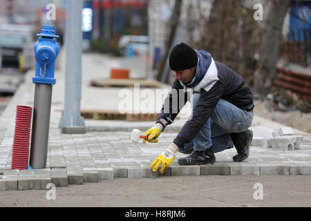 Sofia, Bulgaria - November 15, 2016: Paving stone worker (Bricklayer) is putting down pavers during a construction of a city str Stock Photo
