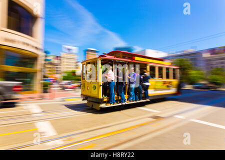 Motion blur pan of moving cable car full of people going past Union Square up Powell Street on a sunny day in California Stock Photo