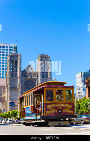 Cable car passing down California Street in front of Grace Cathedral on top of Nob Hill. Vertical Stock Photo