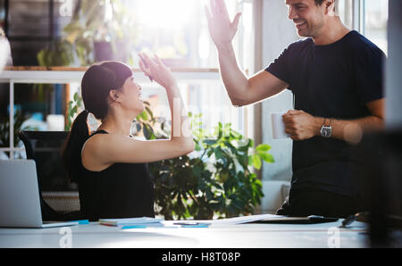 Shot of happy and successful business colleagues giving high five in office. Stock Photo