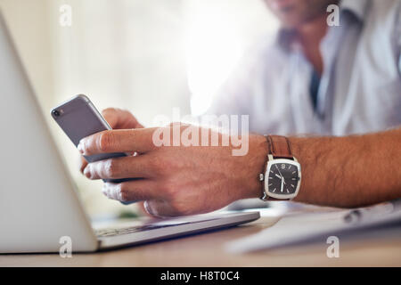 Shot of a man's hands using smart phone. Business man hands busy using mobile phone, focus on the hand and cellphone. Stock Photo