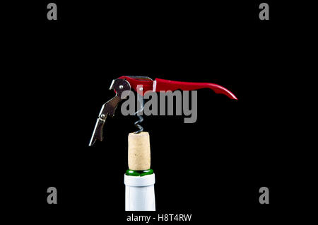 Wine bottle top with a red metal corkscrew in the cork at a black background Stock Photo