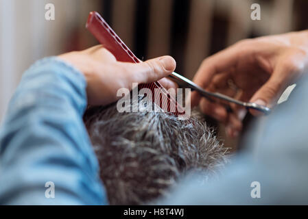 Close up of barber during haircut for grey-haired man Stock Photo