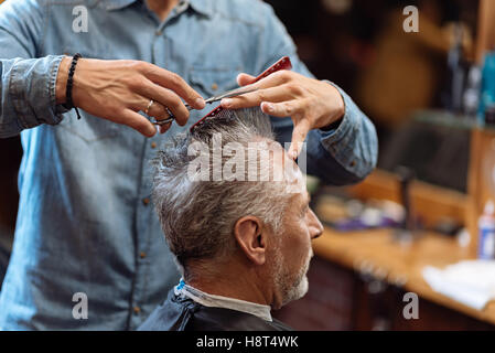 Close up of barber during haircut for grey-haired man Stock Photo