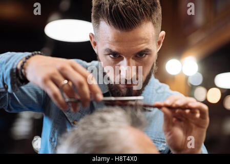 Close up of young male hairdresser cutting hair Stock Photo