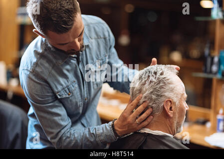 Back view of barber styling seniors client hair Stock Photo