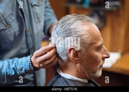 Barber styling hair of senior client Stock Photo