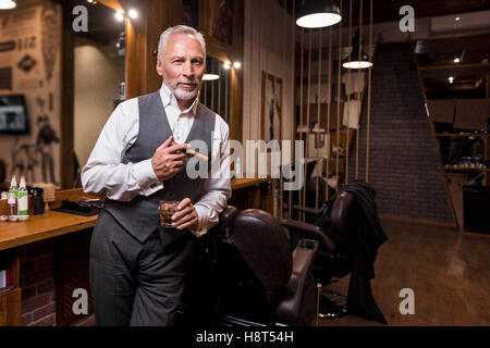 Senior gentleman standing with glass and cigar Stock Photo