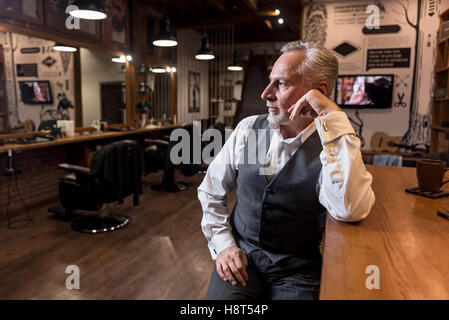 Senior businessman sitting at bar counter and looking aside Stock Photo