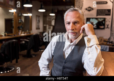 Old man sitting at bar counter and looking forward Stock Photo