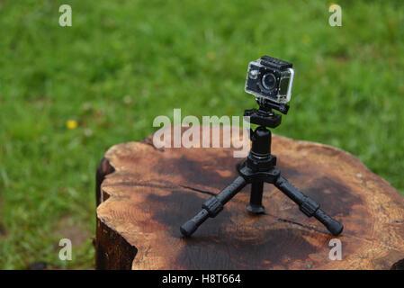 Action camera in rain with waterdrops on it, on a wet log, against green nature background Stock Photo