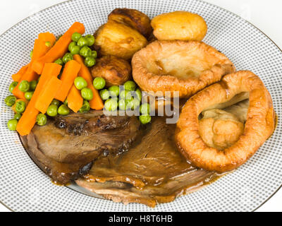 Traditional Authentic English Roast Beef Sunday Lunch With Yorkshire Puddings Vegetables and Gravy Served On A Plate With No People