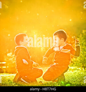 Little twin brothers having fun in the park in a beautiful sunset. Stock Photo