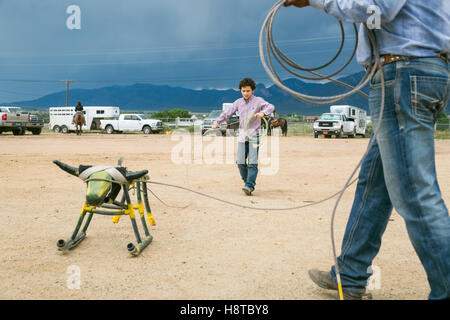 Taos, New Mexico, USA. Small town western rodeo. Cowboys practice roping a stationary cow. Stock Photo