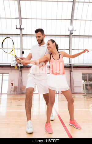 Cheerful tennis instructor teaching young woman Stock Photo