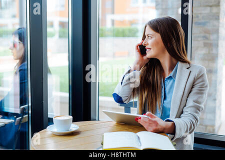 Woman Holding Tablet and Talking on Phone Stock Photo
