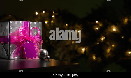 Purple christmas present with tree in the background Stock Photo