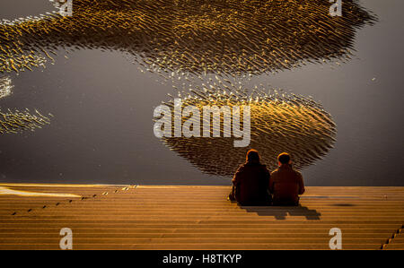 Couple sat on steps down to beach at sunset, Blackpool, Lancashire, UK. Stock Photo