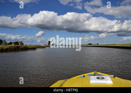 Bow of a yellow boat on the River Yare heading towards Berney Arms Mill on the Norfolk Broads Stock Photo