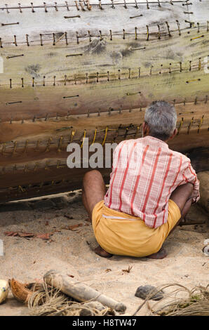 A man fixing a fishing boat, Varkala, Kerala, India Stock Photo