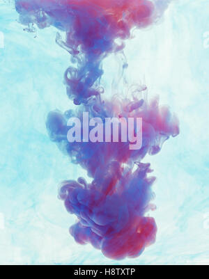 Color drop underwater creating a silk drapery. Ink swirling underwater. Cloud of colorful ink. Blue and magenta mix into violet Stock Photo