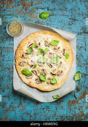 Homemade mushroom pizza with basil leaves over blue wooden background Stock Photo