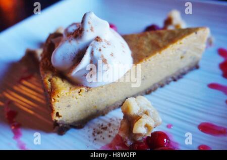 A vegan pumpkin pie cheesecake with coconut whipped cream and fresh cranberries Stock Photo